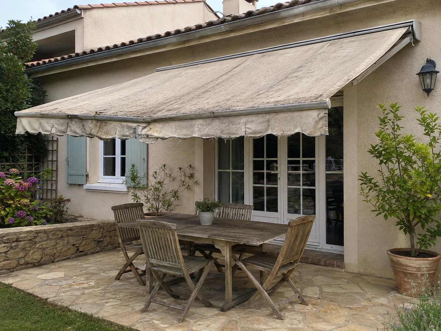 Store banne avant rentoilage avec toile usée et décolorée à remplacer par une toile Dickson.